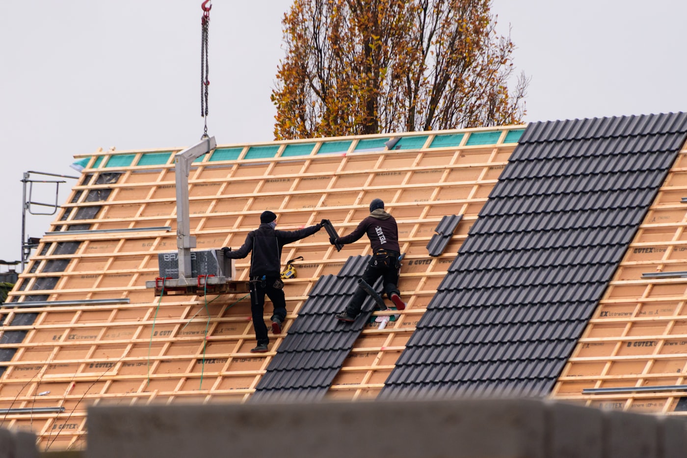 Maestros instalando tejas nuevas sobre la estructura de un techo en obra, cambio de techumbre en Chile