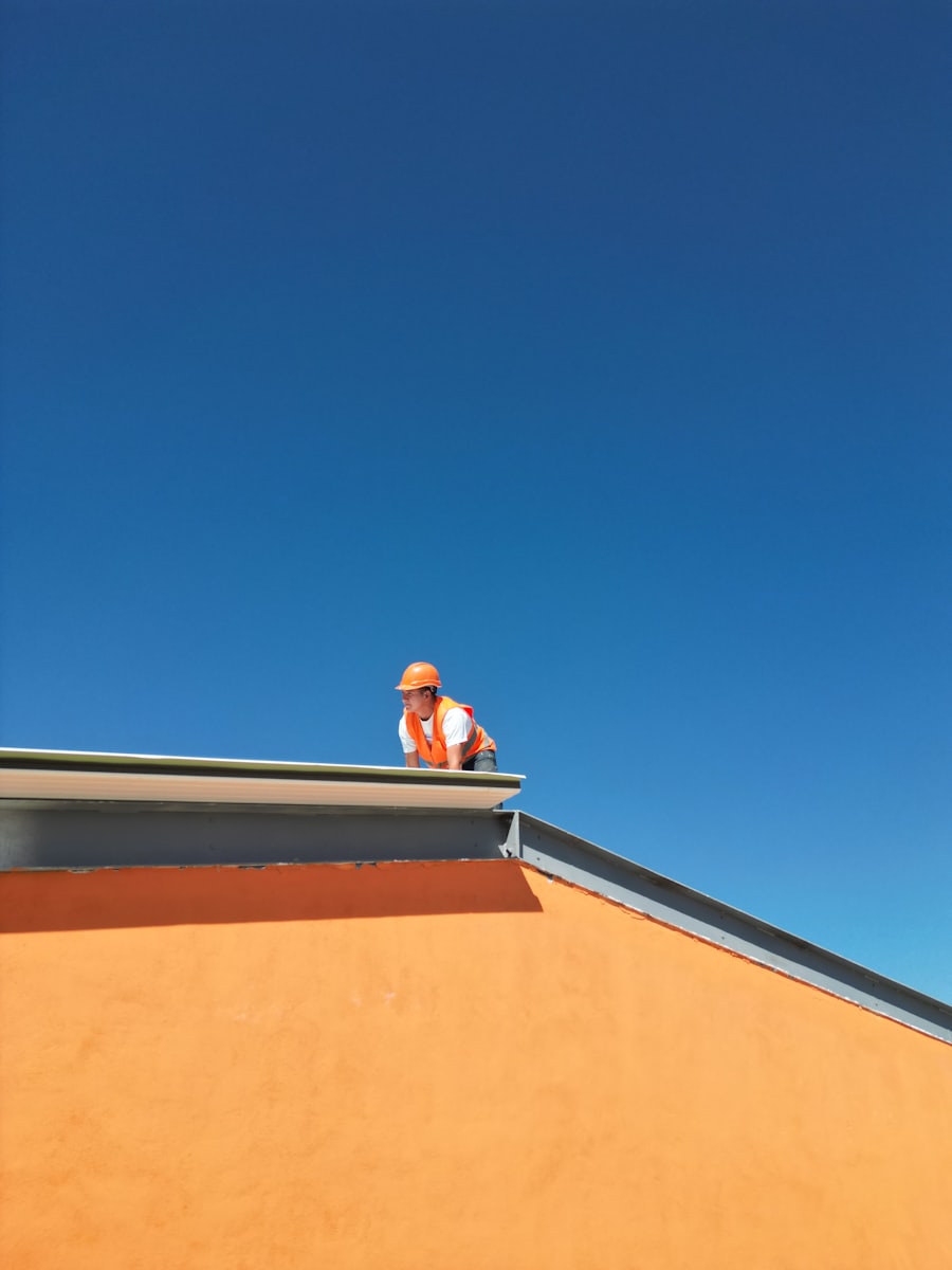 Maestro en el borde de un techo plano bajo cielo azul, impermeabilización de losas en Castro