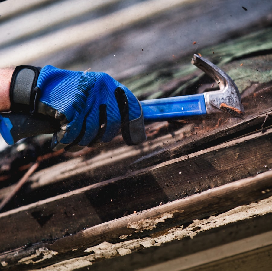 Mano con guante y martillo sobre una plancha de techo, reparación de techos